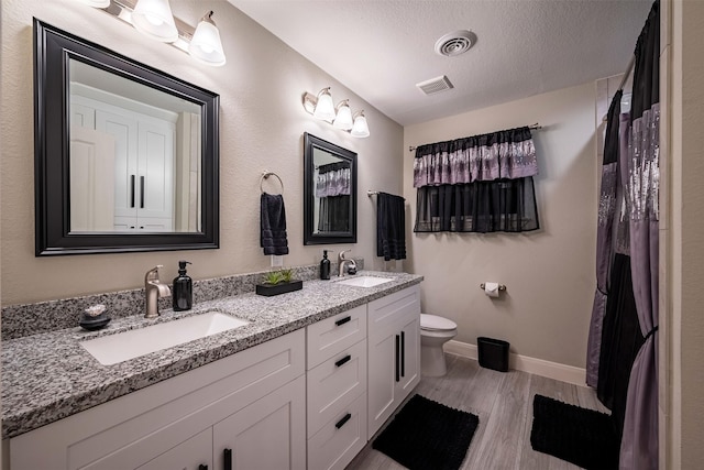 bathroom with a sink, visible vents, a textured ceiling, and wood finished floors