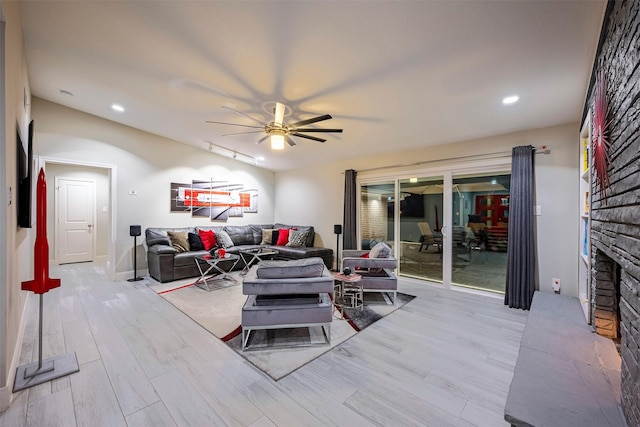 living area featuring a ceiling fan, recessed lighting, an outdoor brick fireplace, light wood finished floors, and vaulted ceiling