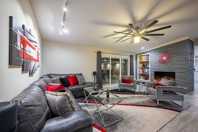 living room with ceiling fan, rail lighting, wood finished floors, and a fireplace