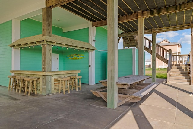 view of patio with outdoor dry bar and stairway