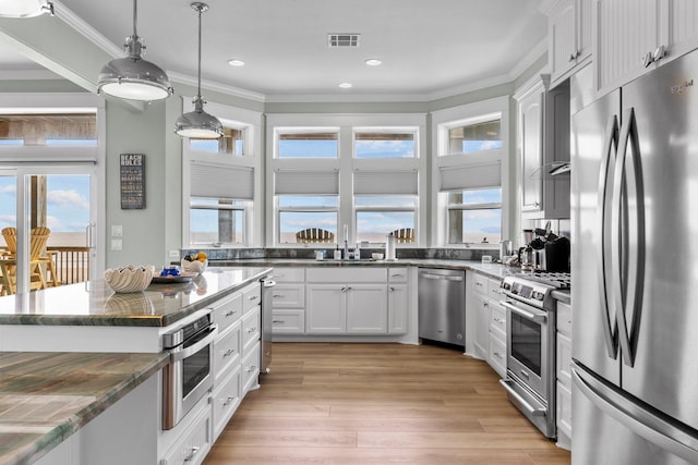 kitchen with stainless steel appliances, visible vents, ornamental molding, and white cabinetry