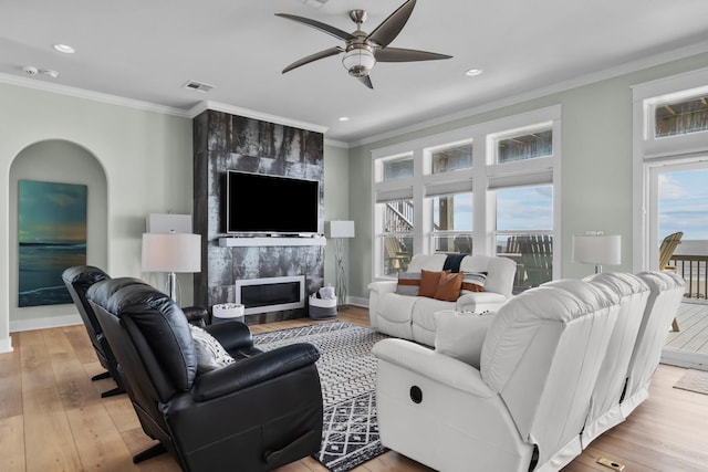 living room with ornamental molding, a fireplace, visible vents, and light wood-style floors