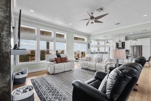 living room featuring visible vents, baseboards, light wood-style flooring, ceiling fan, and ornamental molding