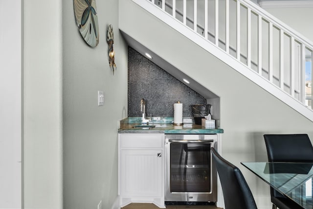 bar featuring beverage cooler, an accent wall, wet bar, a high ceiling, and a sink