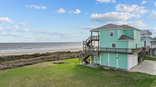 rear view of property with a yard, a beach view, a deck with water view, driveway, and stairs