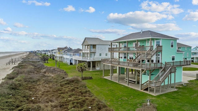 rear view of house featuring a patio, a deck with water view, stairs, a lawn, and a residential view