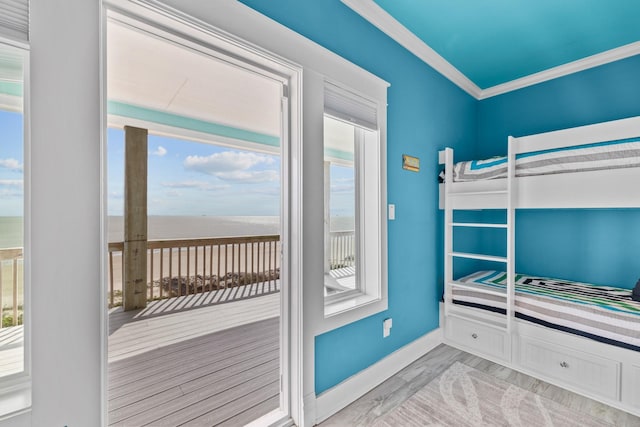 unfurnished bedroom with baseboards, a water view, access to outside, crown molding, and light wood-type flooring