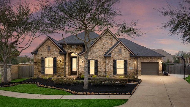 view of front of home with brick siding, fence, a shingled roof, driveway, and a garage