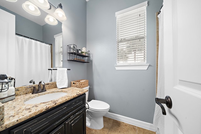 bathroom featuring baseboards, vanity, tile patterned floors, and toilet