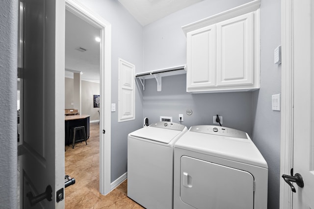 laundry area with baseboards, visible vents, washing machine and dryer, and cabinet space