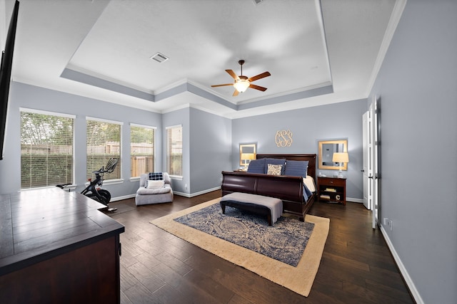 bedroom with dark wood-style flooring, ornamental molding, visible vents, and a tray ceiling