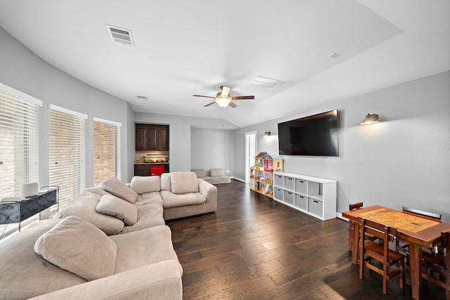 living area featuring dark wood-style floors, visible vents, baseboards, vaulted ceiling, and ceiling fan