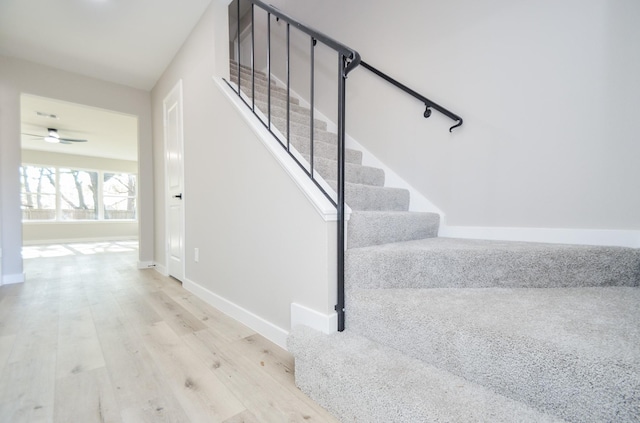 stairway with baseboards, ceiling fan, and wood finished floors