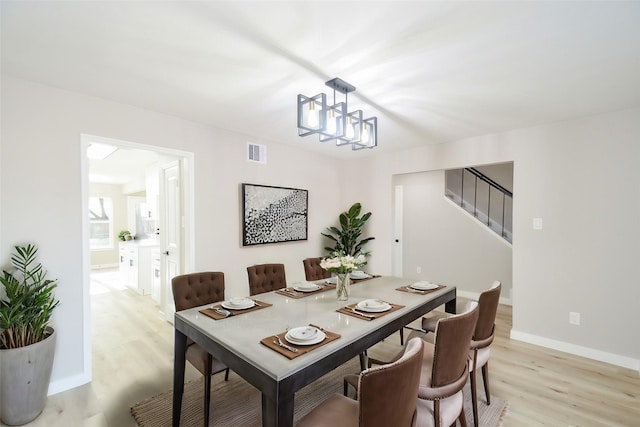 dining space with baseboards, stairs, visible vents, and light wood-style floors