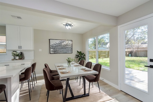 dining space with visible vents, an inviting chandelier, baseboards, and light wood finished floors