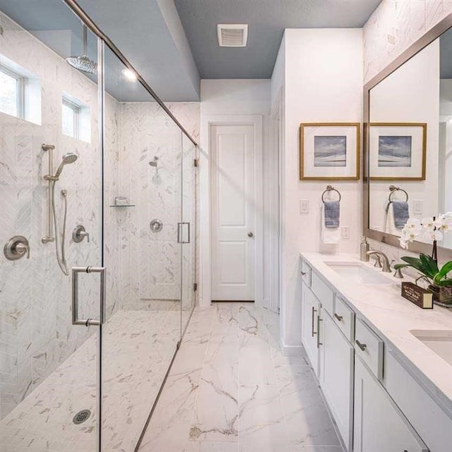 bathroom with marble finish floor, double vanity, visible vents, a sink, and a shower stall