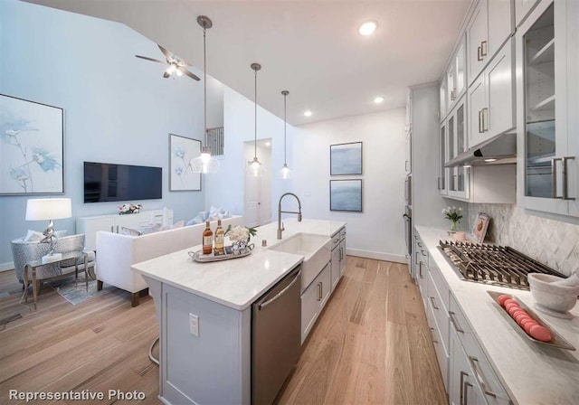 kitchen featuring light countertops, glass insert cabinets, a kitchen island with sink, and appliances with stainless steel finishes