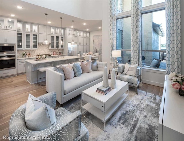 living room featuring recessed lighting, a high ceiling, and light wood-type flooring