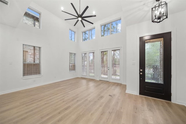 foyer entrance featuring baseboards, visible vents, a towering ceiling, and light wood-style floors