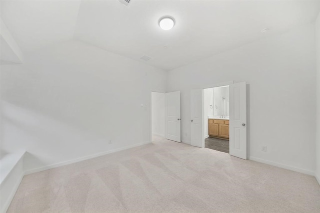 unfurnished bedroom with ensuite bathroom, baseboards, and light colored carpet