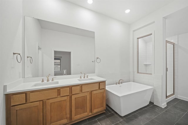 full bath with a sink, a freestanding bath, double vanity, and a stall shower