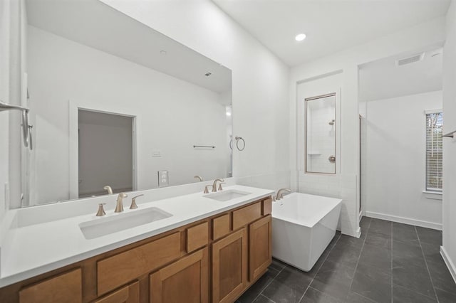 bathroom with double vanity, a freestanding bath, visible vents, and a sink