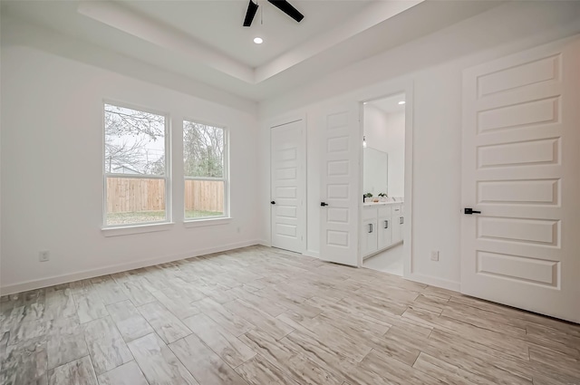 9418 Madera Rd, Houston, TX 77078 - unfurnished bedroom with light wood-style floors, connected bathroom, a raised ceiling, baseboards, and recessed lighting
