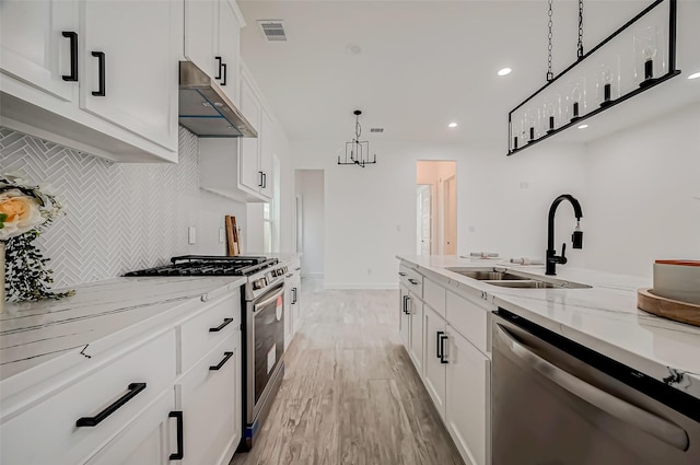 9418 Madera Rd, Houston, TX 77078 - kitchen with stainless steel appliances, a sink, under cabinet range hood, decorative backsplash, and light stone counters
