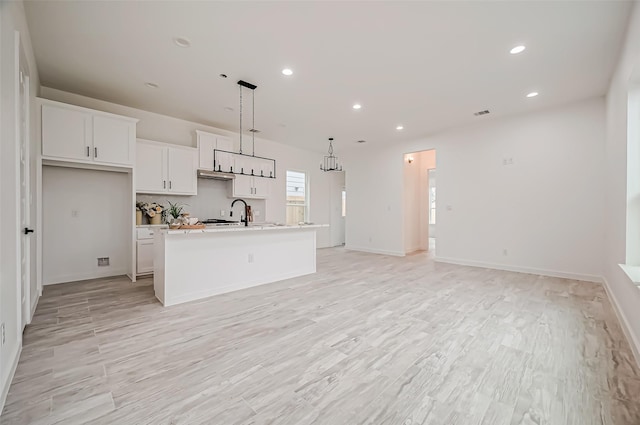 9418 Madera Rd, Houston, TX 77078 - kitchen with an island with sink, open floor plan, white cabinetry, recessed lighting, and decorative light fixtures