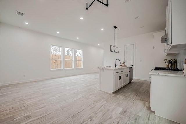 9418 Madera Rd, Houston, TX 77078 - kitchen featuring a sink, extractor fan, stainless steel dishwasher, light stone counters, and a kitchen island with sink