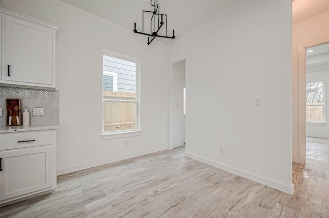 9418 Madera Rd, Houston, TX 77078 - unfurnished dining area featuring a chandelier, light wood finished floors, and baseboards