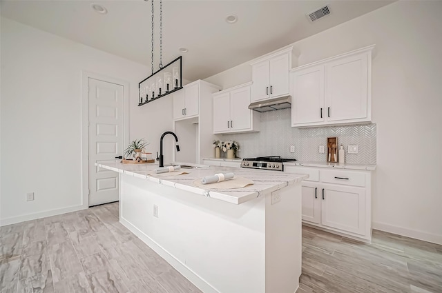 9418 Madera Rd, Houston, TX 77078 - kitchen featuring a sink, under cabinet range hood, an island with sink, white cabinetry, and decorative backsplash