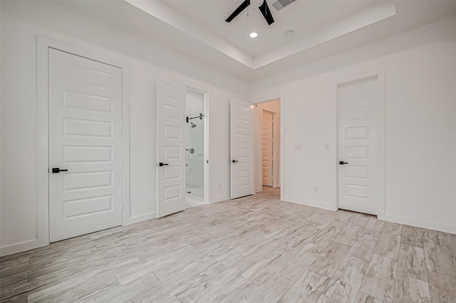 9418 Madera Rd, Houston, TX 77078 - unfurnished bedroom with a tray ceiling, connected bathroom, light wood-type flooring, baseboards, and recessed lighting