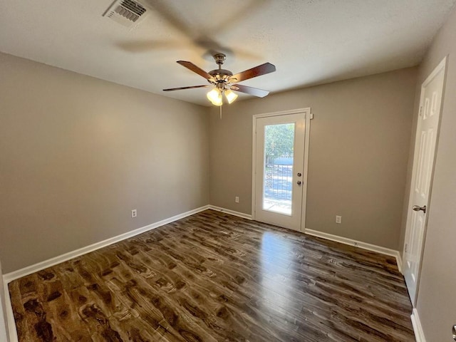 spare room with ceiling fan, dark wood finished floors, visible vents, and baseboards