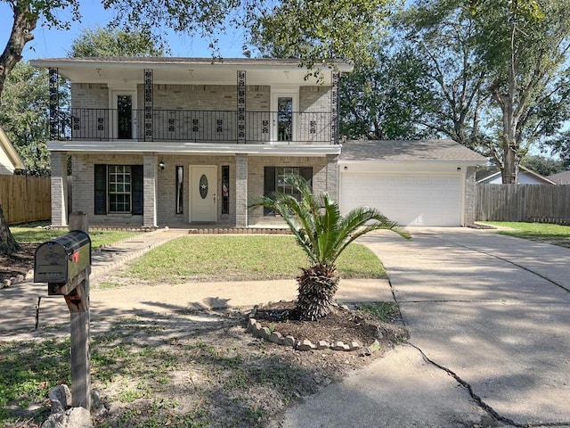 front of property with a balcony, an attached garage, fence, and brick siding