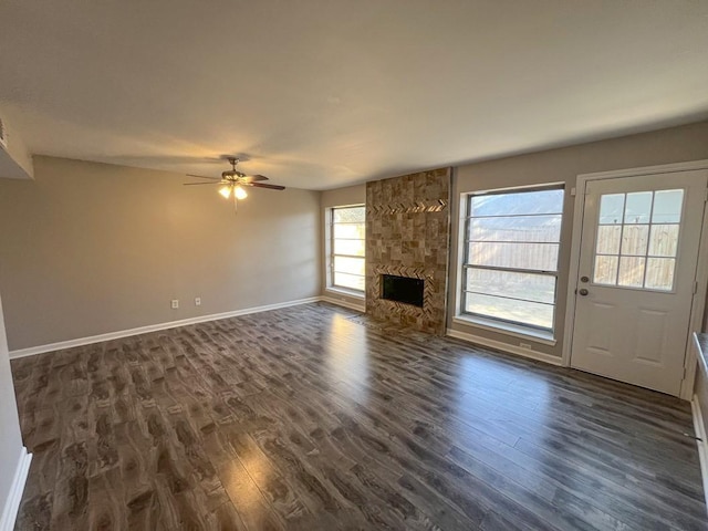 unfurnished living room featuring a ceiling fan, a fireplace, baseboards, and dark wood-type flooring