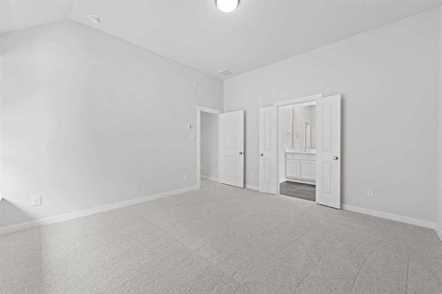 2666 Woodforest Pkwy N, Montgomery, TX 77316 - unfurnished bedroom featuring visible vents, lofted ceiling, ensuite bath, carpet floors, and baseboards