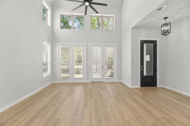 2666 Woodforest Pkwy N, Montgomery, TX 77316 - entryway featuring visible vents, baseboards, light wood-type flooring, ceiling fan with notable chandelier, and a towering ceiling