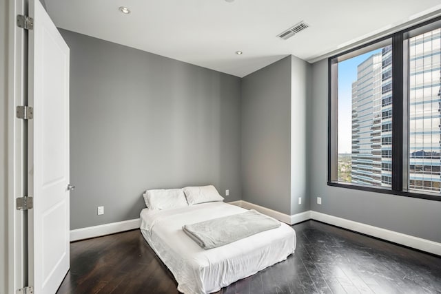 bedroom featuring recessed lighting, visible vents, dark wood finished floors, baseboards, and a city view