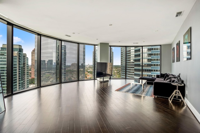 unfurnished living room with a city view, wood finished floors, baseboards, and a wall of windows