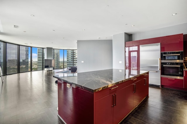 kitchen with a large island, open floor plan, a wall of windows, stainless steel built in fridge, and modern cabinets