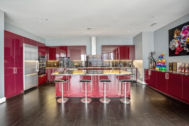 kitchen featuring a kitchen bar, light stone countertops, modern cabinets, and wall chimney range hood