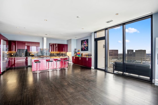 kitchen featuring a city view, open floor plan, a kitchen island, a breakfast bar area, and wall chimney range hood