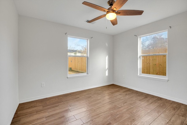 spare room with light wood-type flooring, visible vents, baseboards, and a ceiling fan