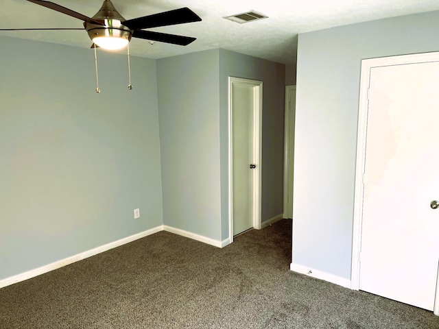 spare room featuring a ceiling fan, visible vents, dark carpet, and baseboards