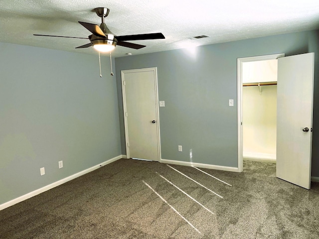 unfurnished bedroom with a textured ceiling, a spacious closet, visible vents, and baseboards