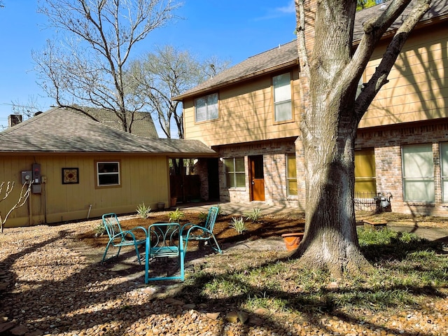 back of house featuring a patio area, brick siding, and a chimney