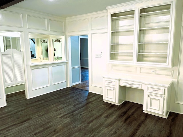 mudroom with dark wood-style floors, a decorative wall, and built in desk