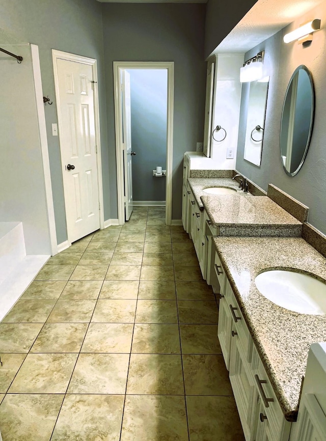 full bathroom featuring baseboards, two vanities, a sink, and tile patterned floors