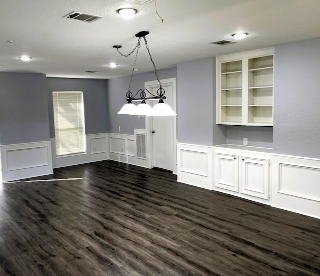 interior space featuring a textured ceiling, visible vents, and dark wood-style flooring